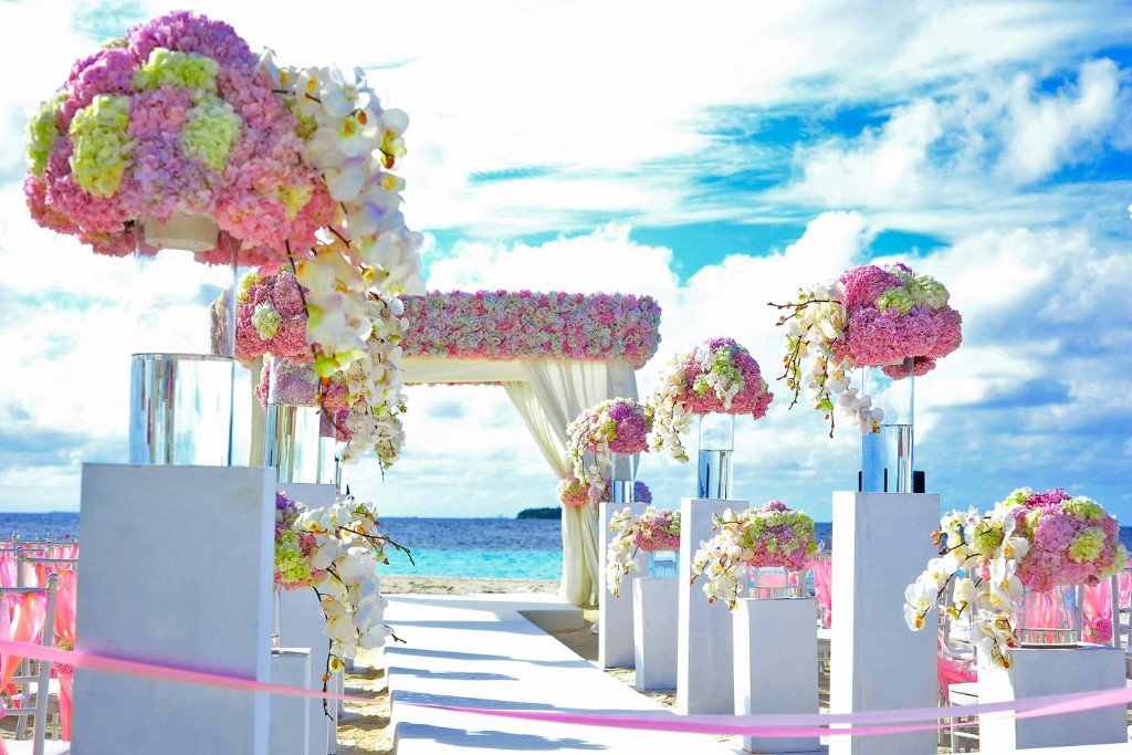 Beachfront destination wedding aisle with floral arrangements and blue ocean backdrop